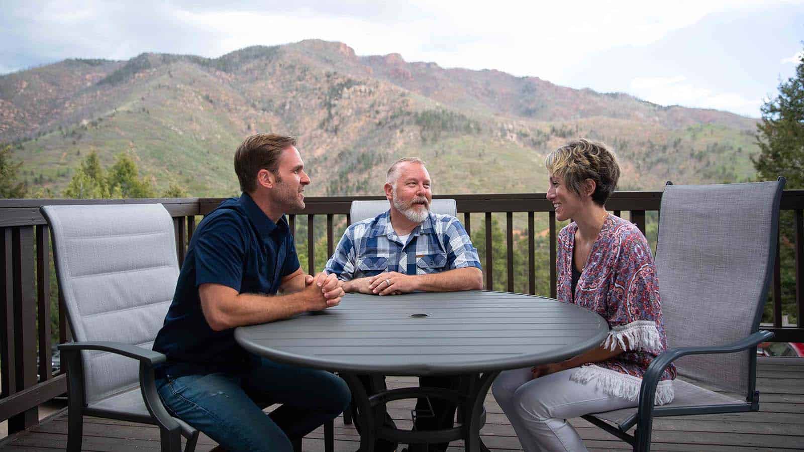 Two parents sit across the table from a licensed clinician for family therapy.