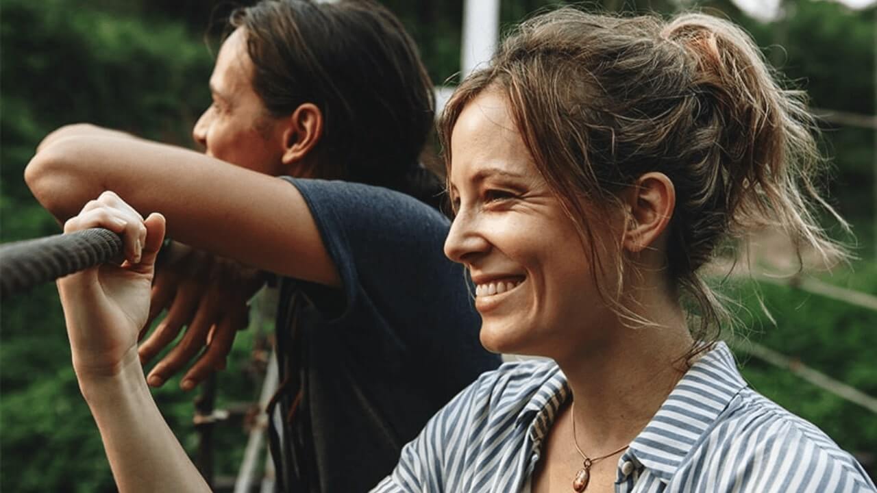 there are two women standing on a bridge with a rope