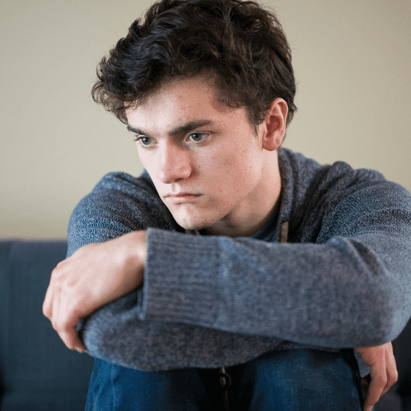 arafed young man sitting on a couch with his arms crossed