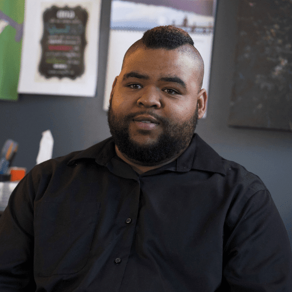 there is a man sitting at a desk with a black shirt