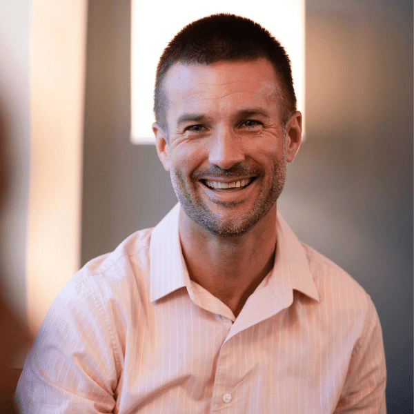 smiling man in a pink shirt with a white shirt on