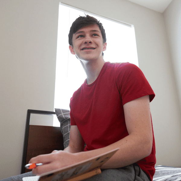 arafed man sitting on a bed with a clipboard in his hand