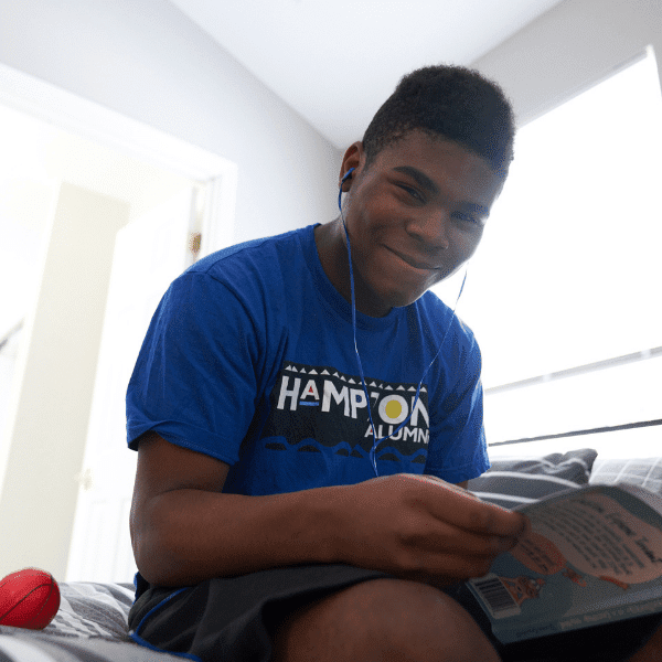 arafed boy sitting on a bed reading a book