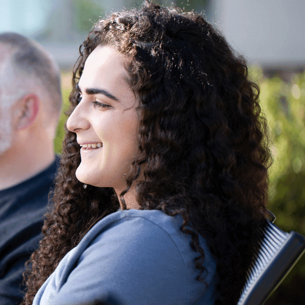 there is a woman sitting in a chair with a man in the background
