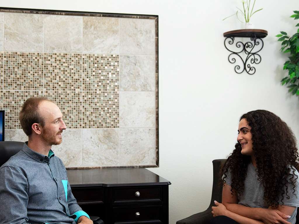 there is a man and woman sitting in a chair talking