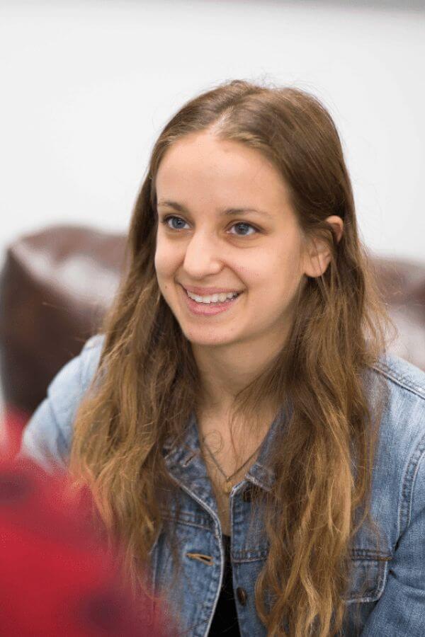 arafed woman with long hair smiling while sitting in a chair
