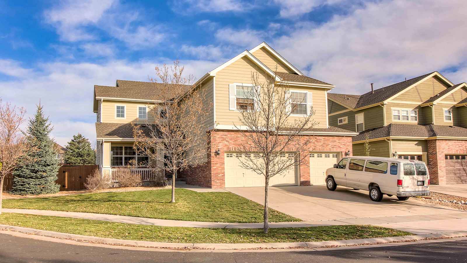 there is a van parked in front of a house with a tree in the yard