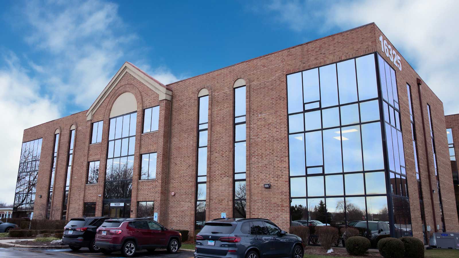 cars parked in front of a large brick building with a sky background