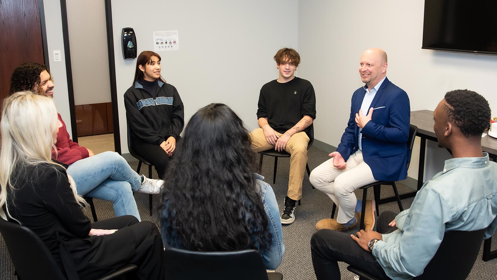 several people sitting in a circle in a room with a tv