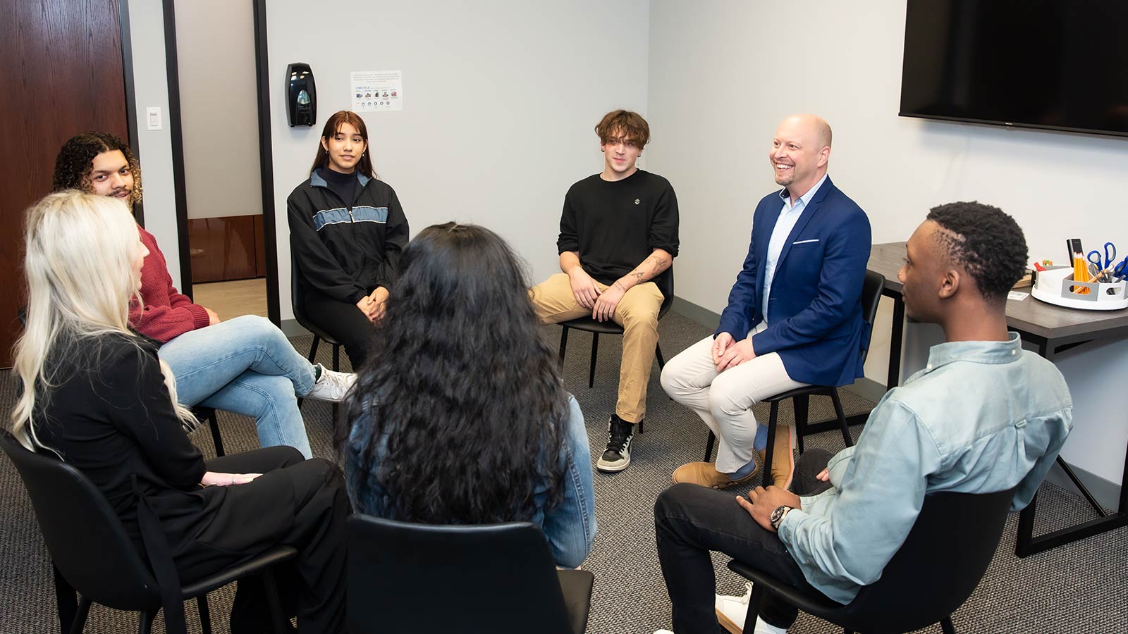 several people sitting in a circle in a room with a tv