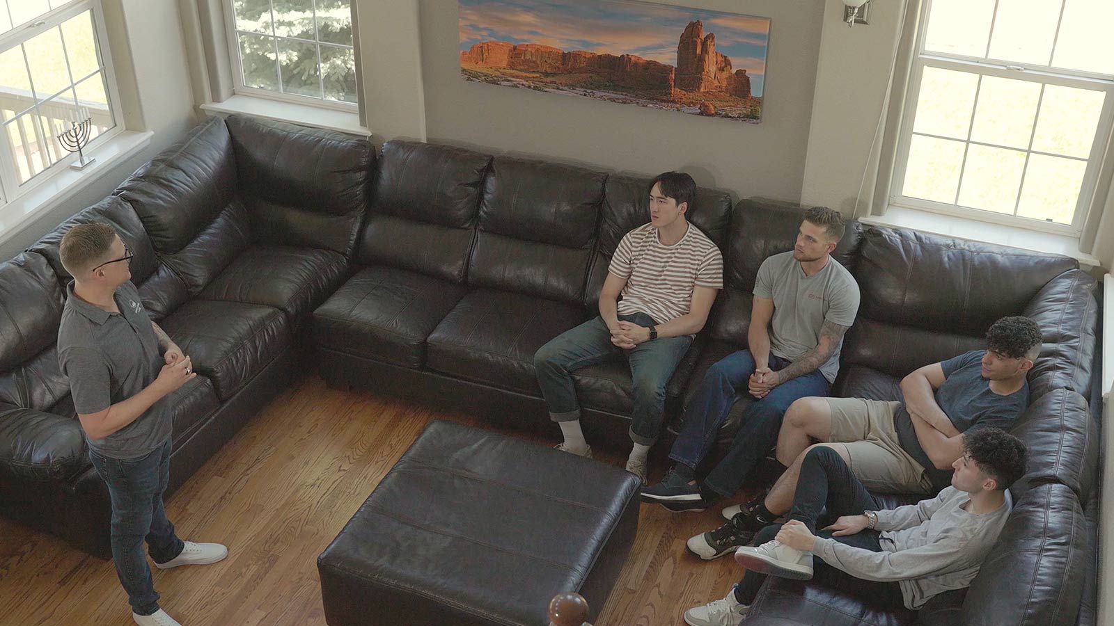 there are four men sitting on a couch in a living room