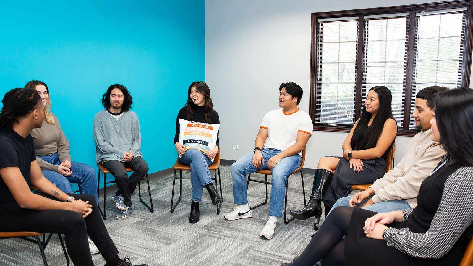 several people sitting in a circle in a room with a blue wall