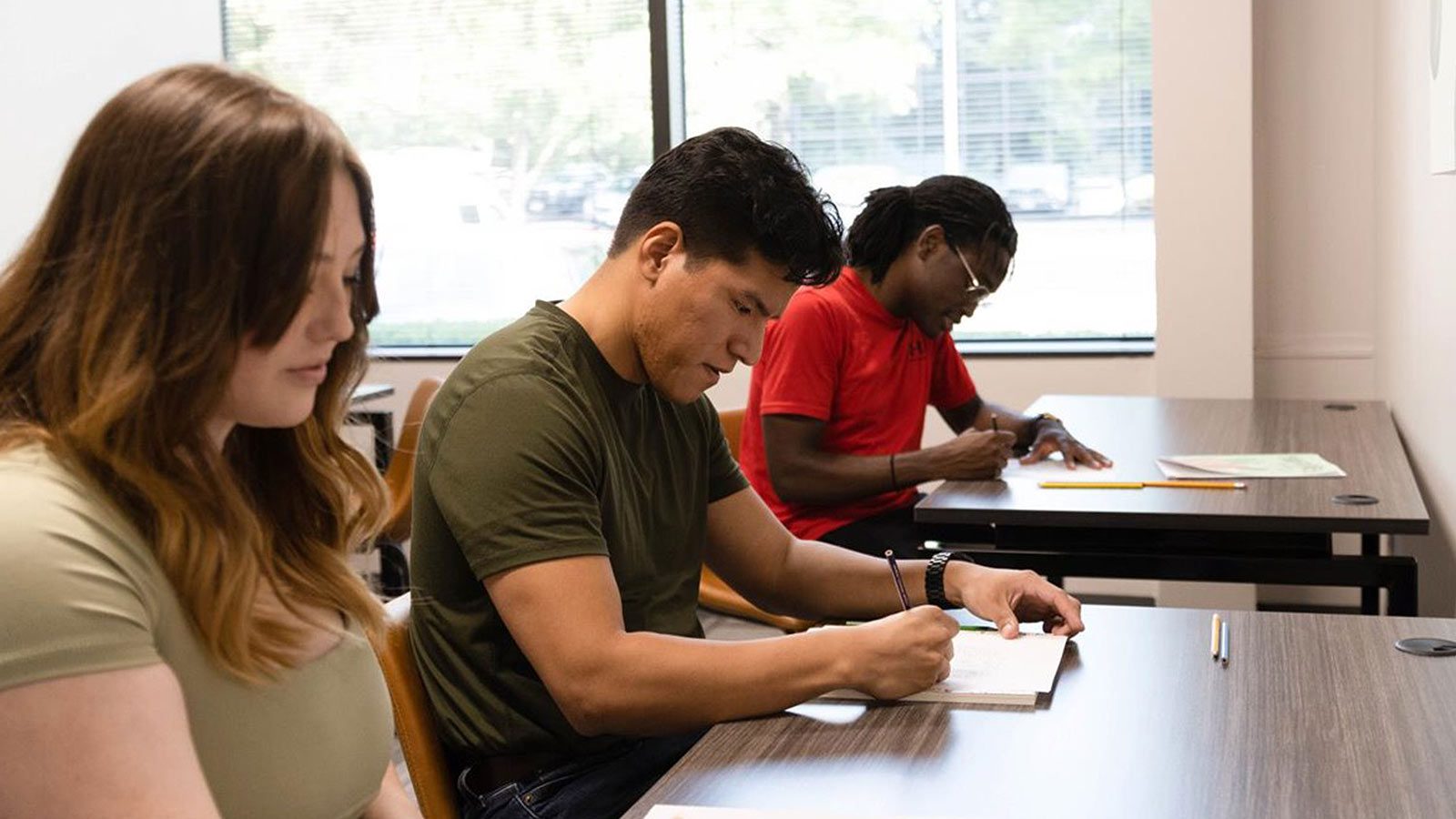 students sitting at a table writing in a classroom