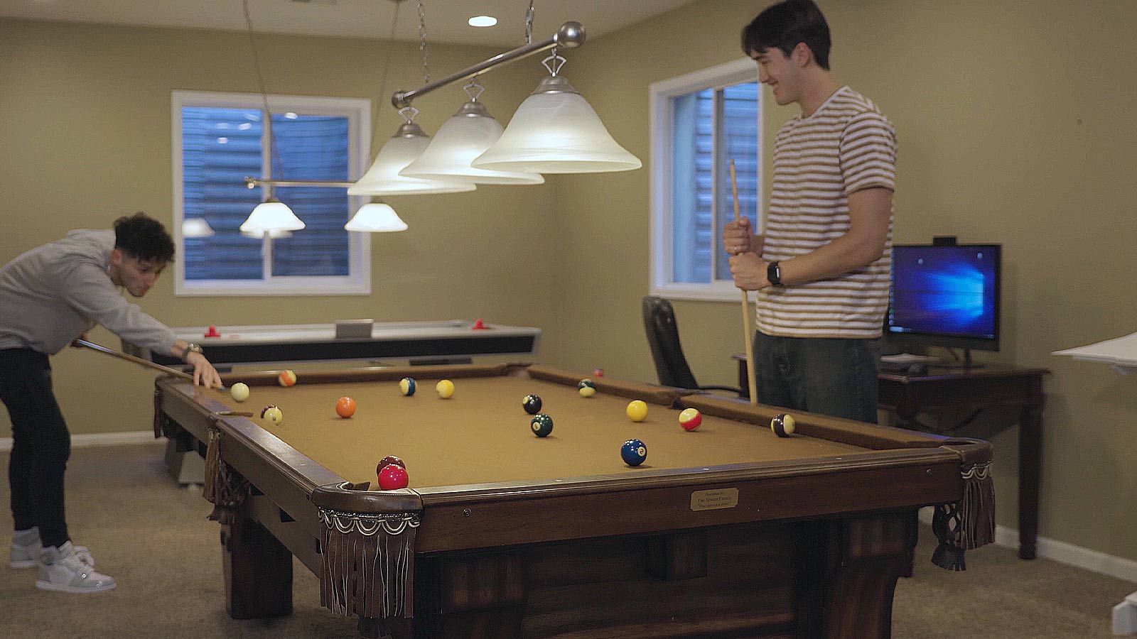 they are playing pool in the living room with a tv