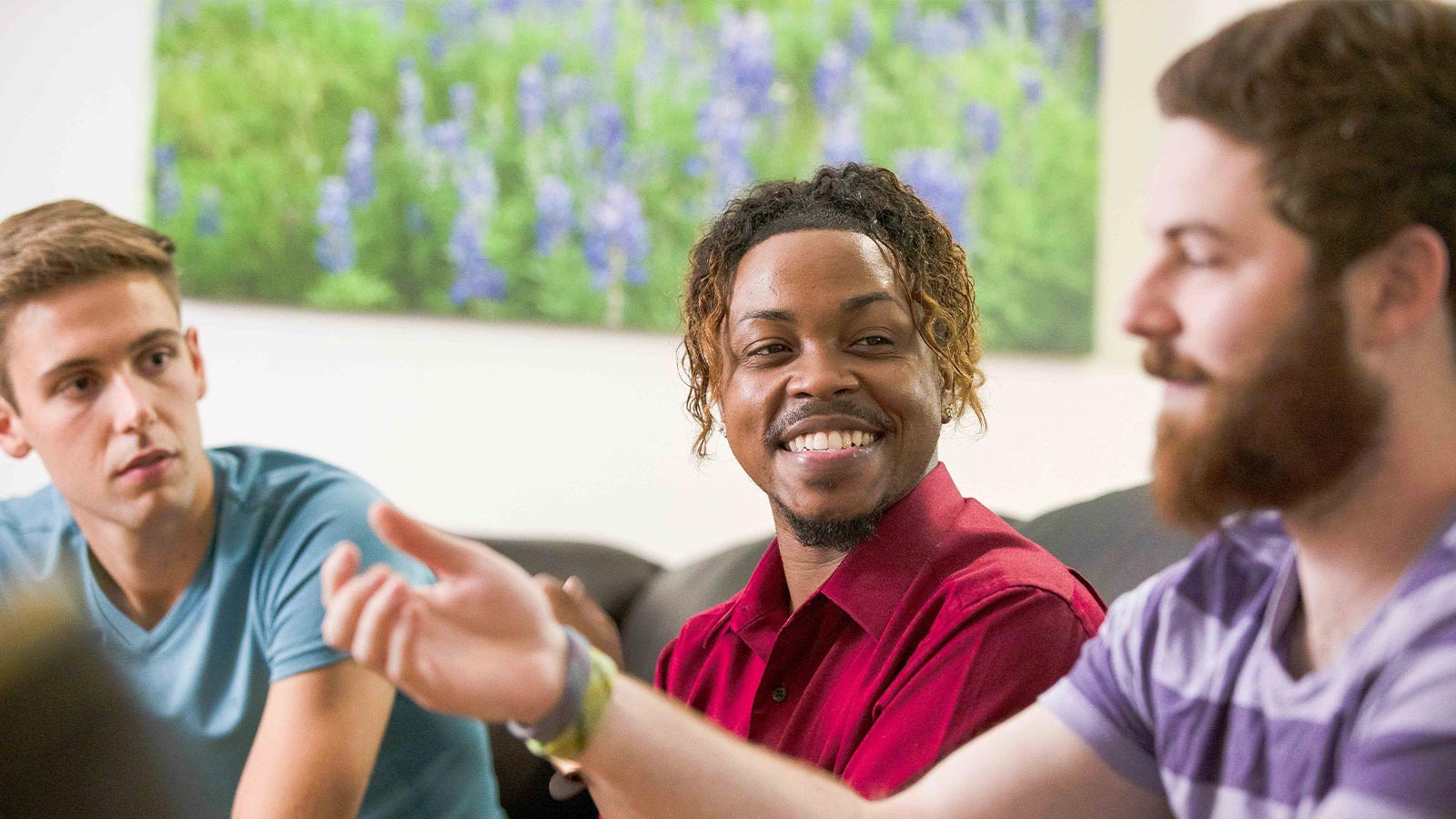 there are three men sitting at a table with a remote