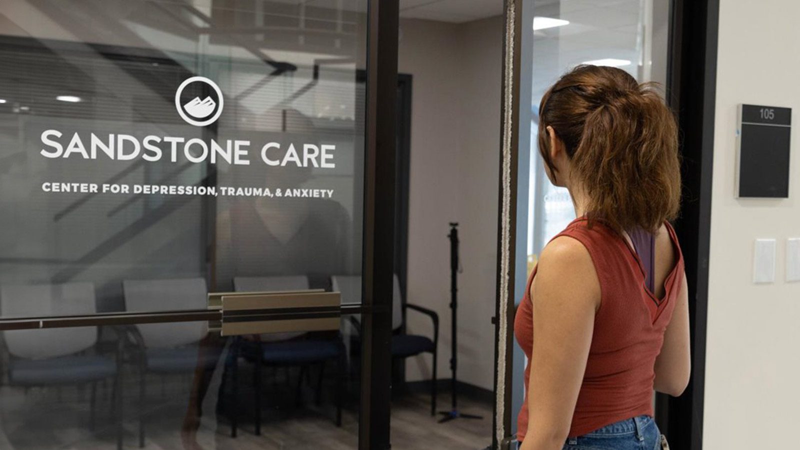 arafed woman standing in front of a glass door with a sign that says sandstone care