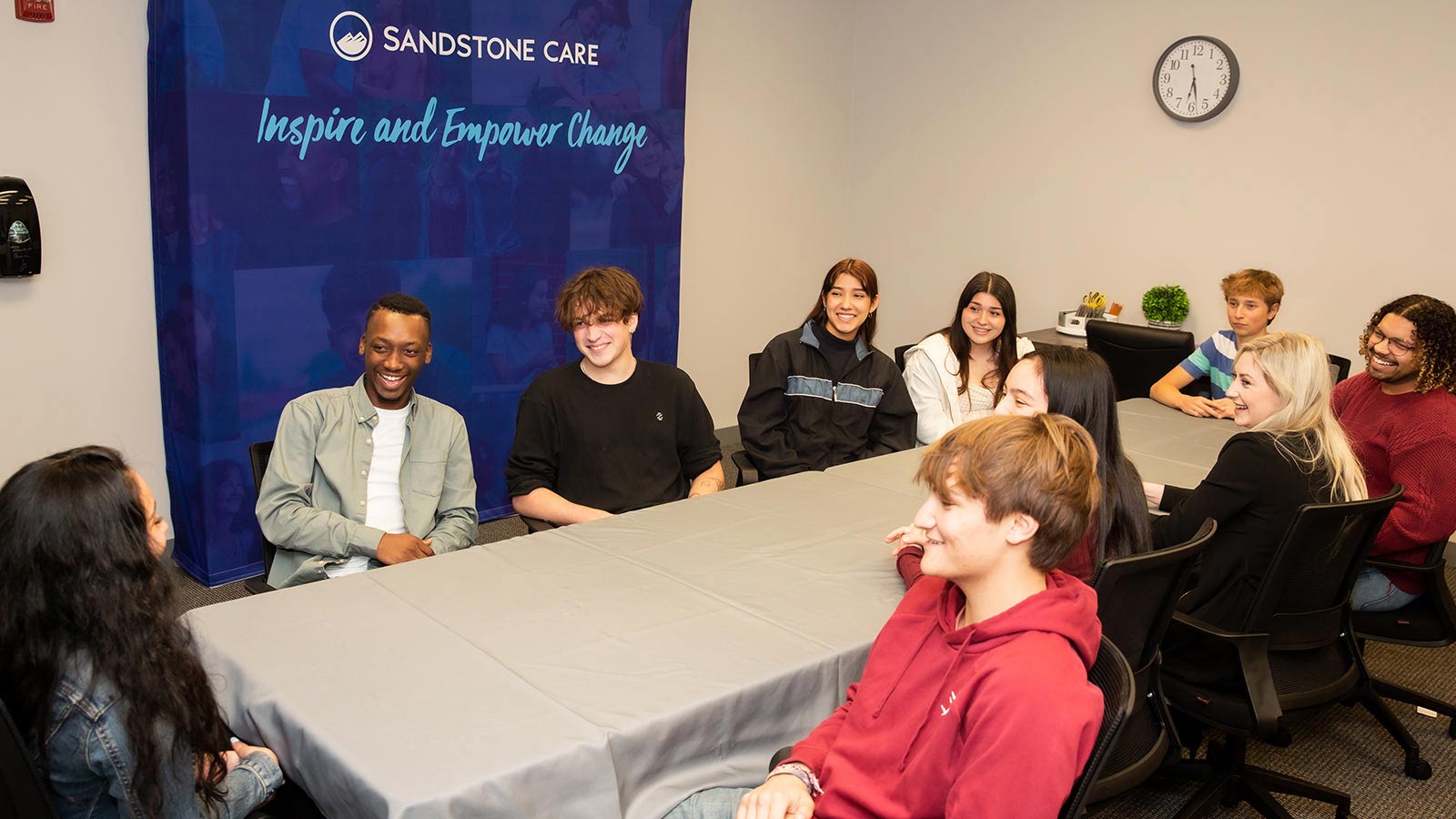 several people sitting around a table with a blue banner behind them
