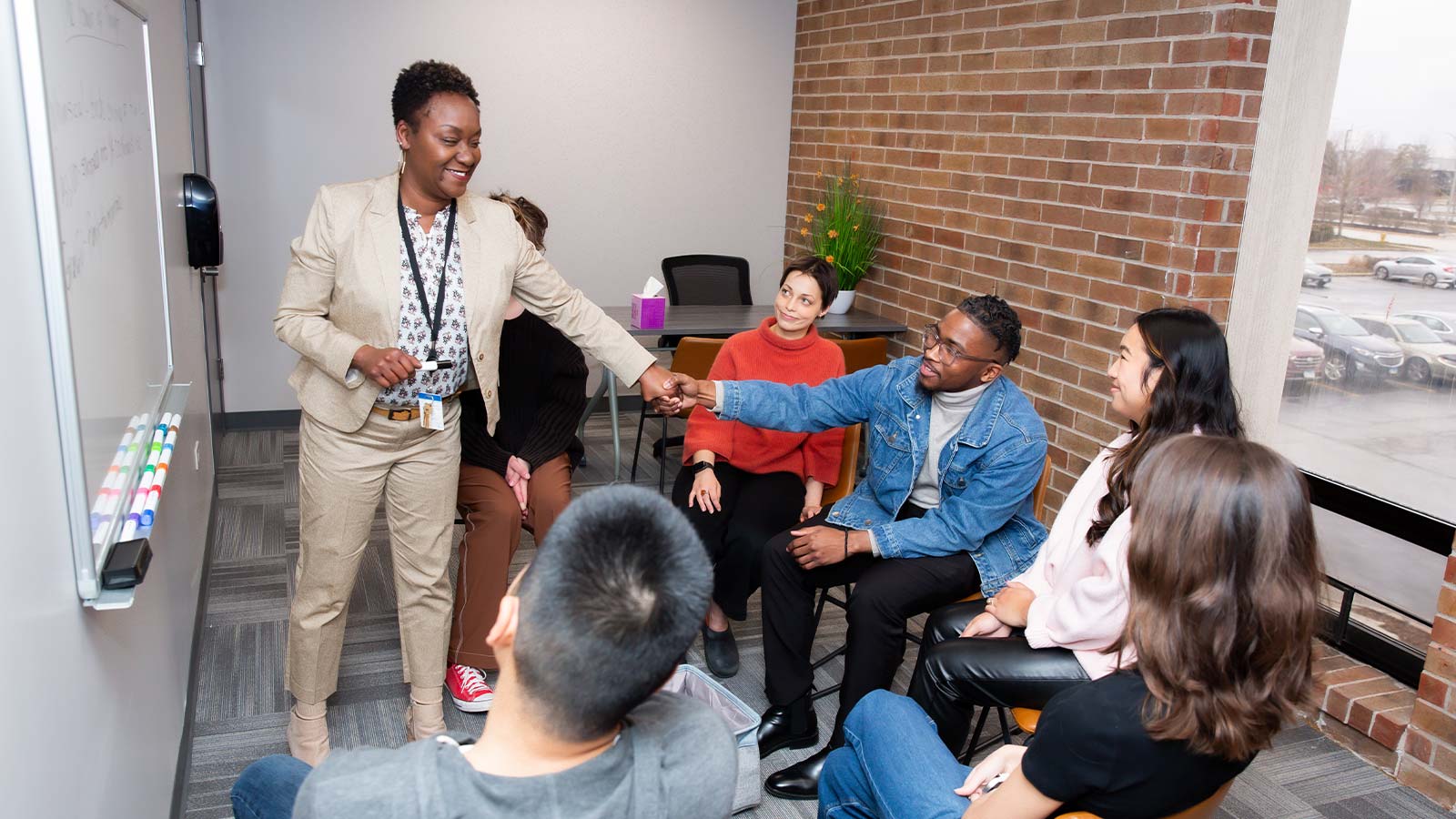 several people are sitting in a room and one is shaking hands