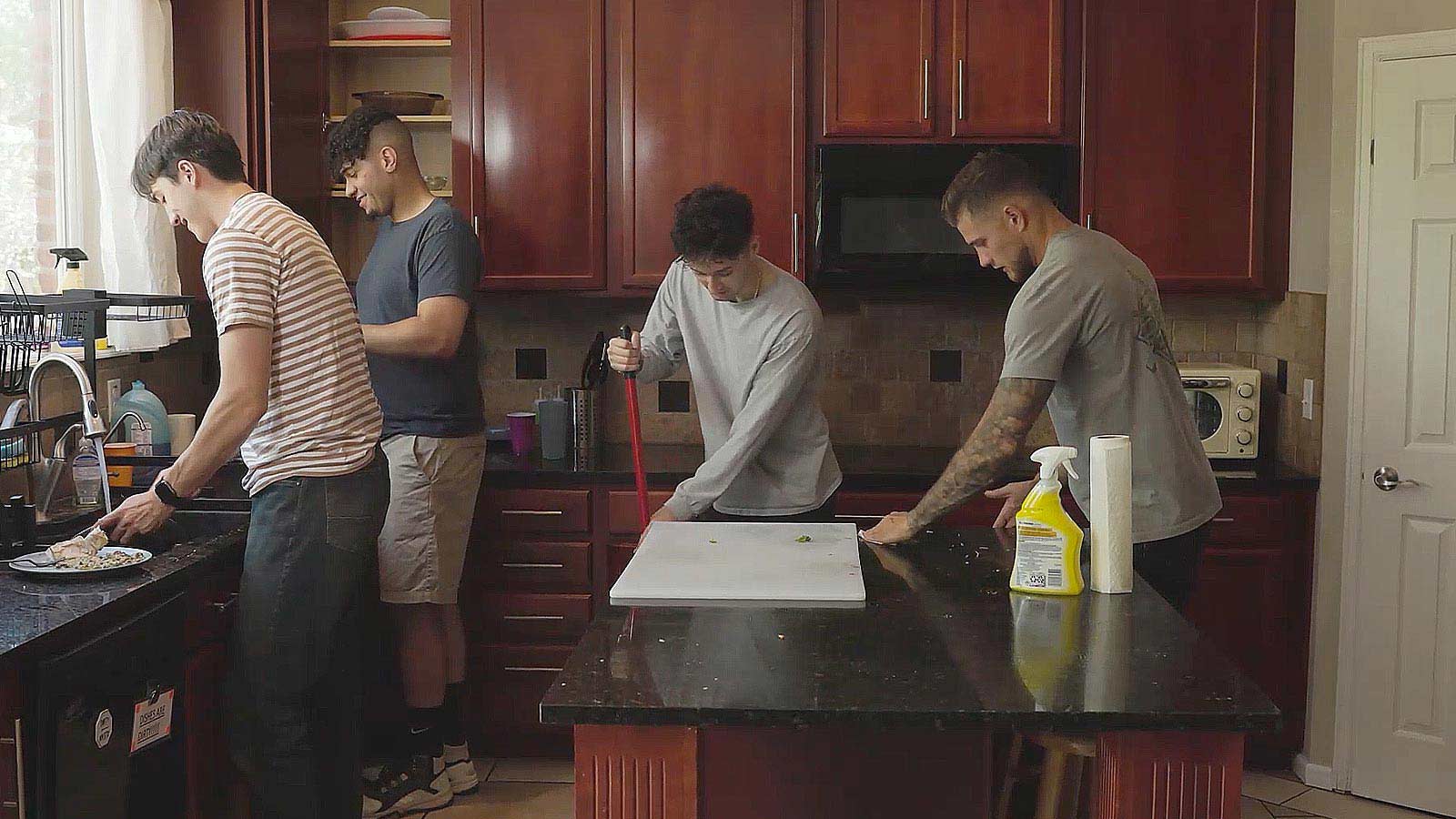 several men are in a kitchen preparing food and cleaning the counter
