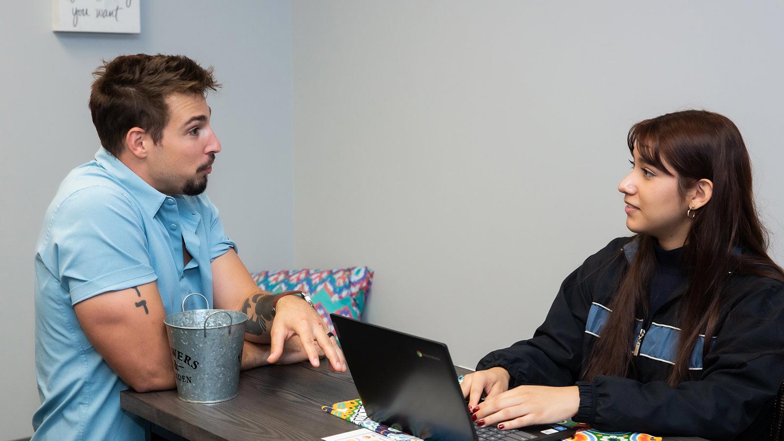 there is a man and woman sitting at a table with a laptop