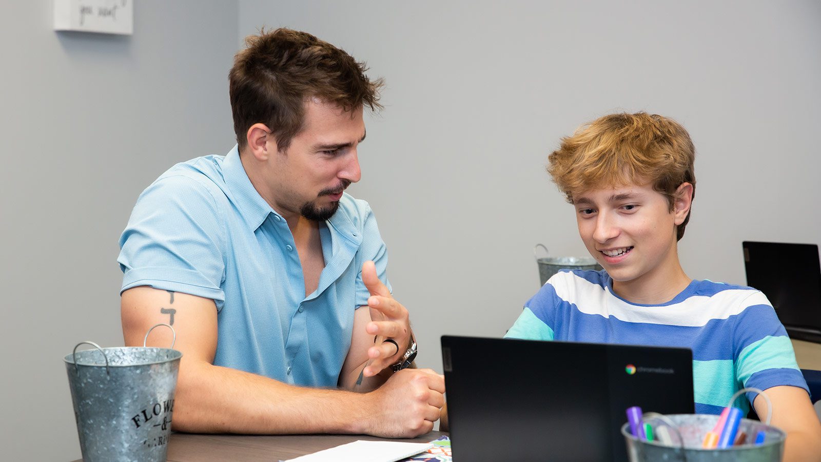 there is a man and a boy sitting at a table with a laptop