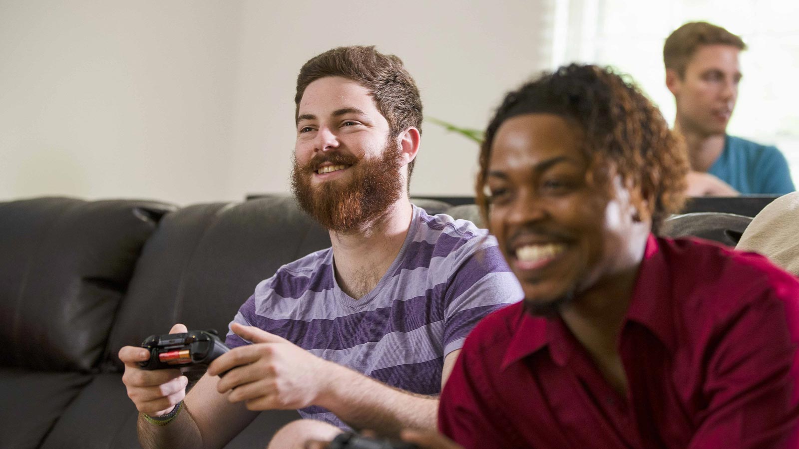 there are two men sitting on a couch playing a video game