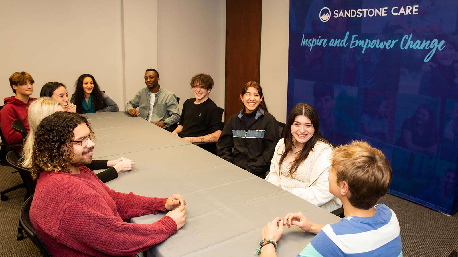 several people sitting at a table with a sign in front of them