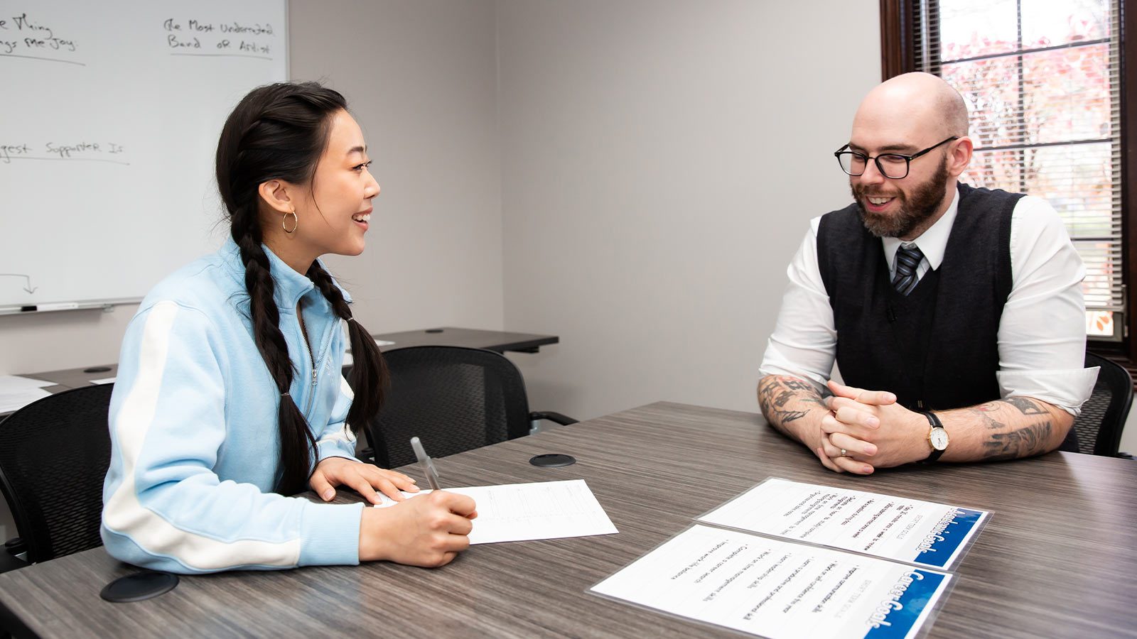 smiling woman sitting at a table with a man in a vest