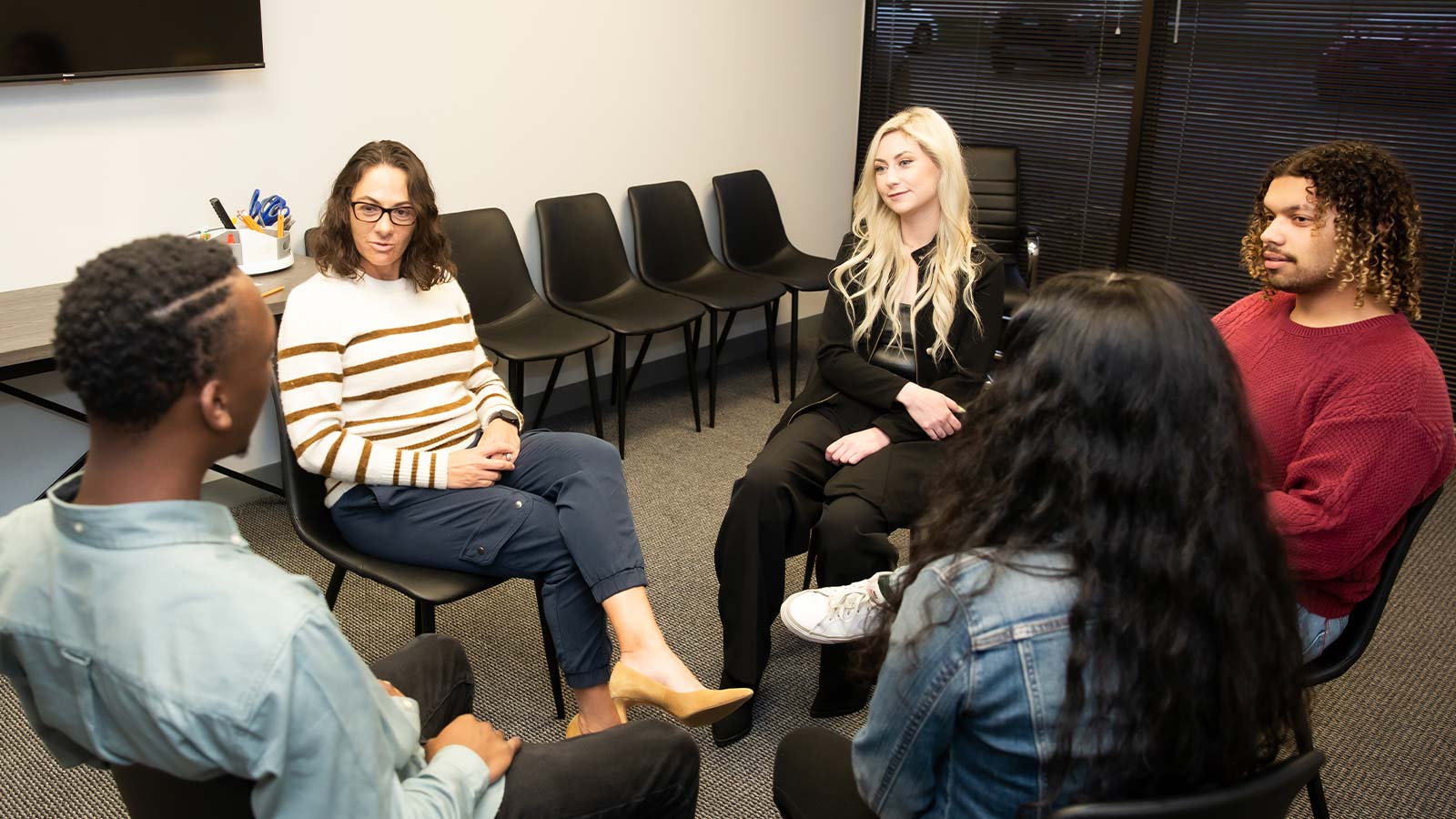 several people sitting in a circle in a room with chairs