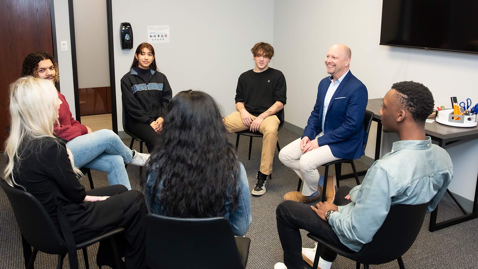 several people sitting in a circle in a room with a tv
