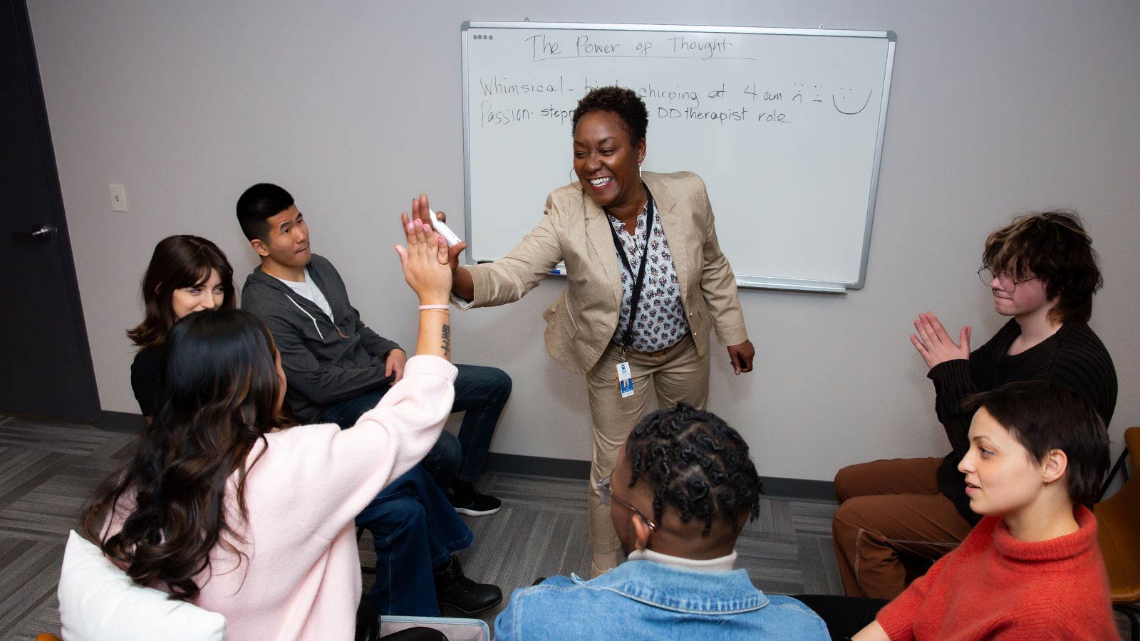 several people sitting in a circle and one woman is giving a high five