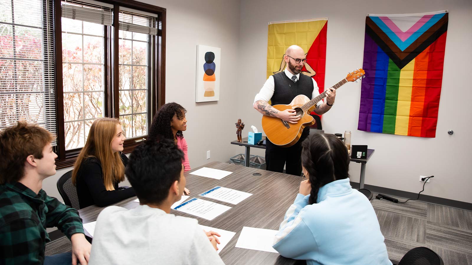 there is a man playing a guitar in a room with people