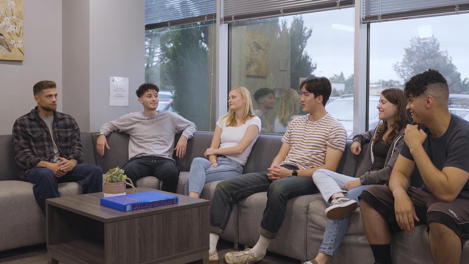 several people sitting on a couch in a room with a window