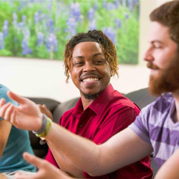 three men sitting on a couch laughing and laughing