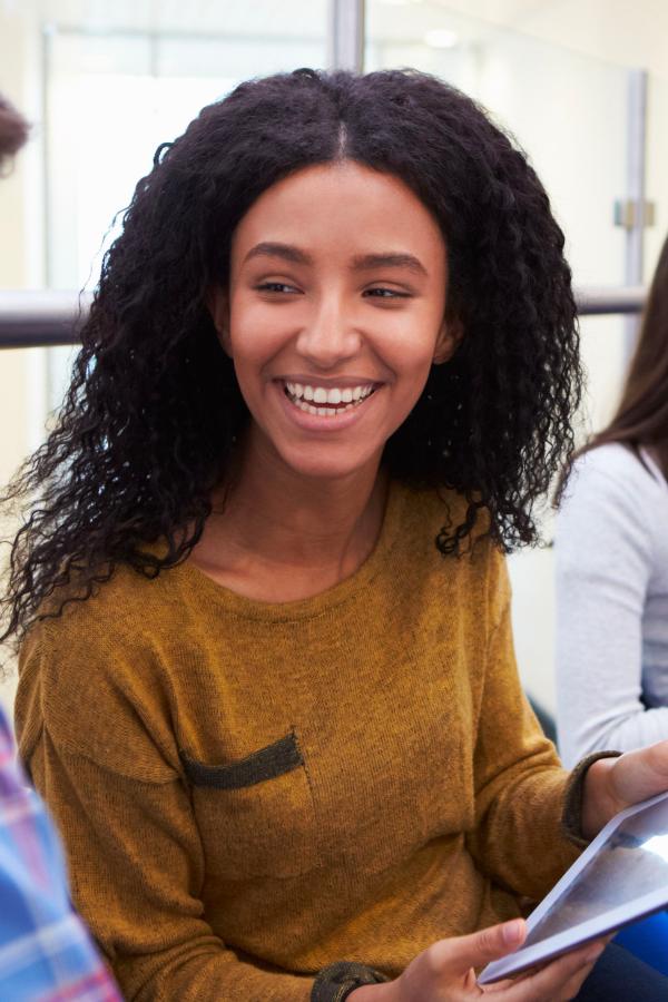 smiling woman sitting in a group of people holding papers