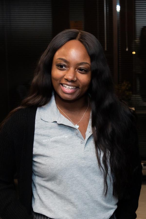 smiling woman in a gray shirt and black cardigan sweater