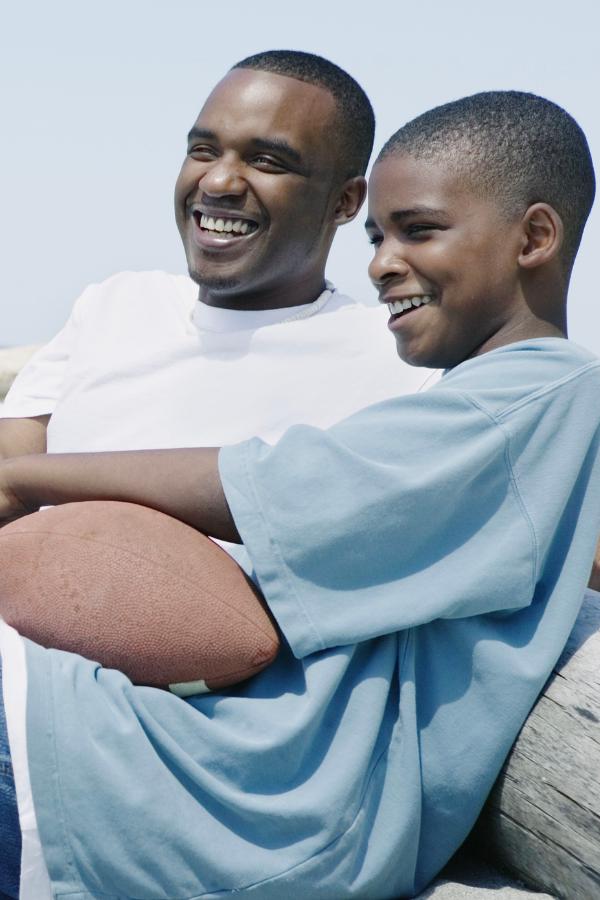 there are two men sitting on a bench with a football