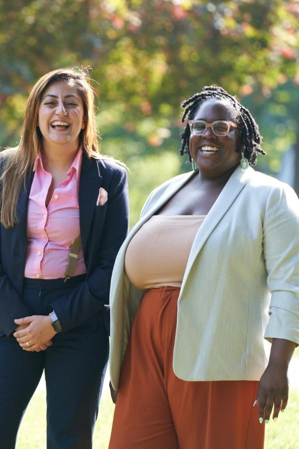 two women standing in a park smiling and laughing
