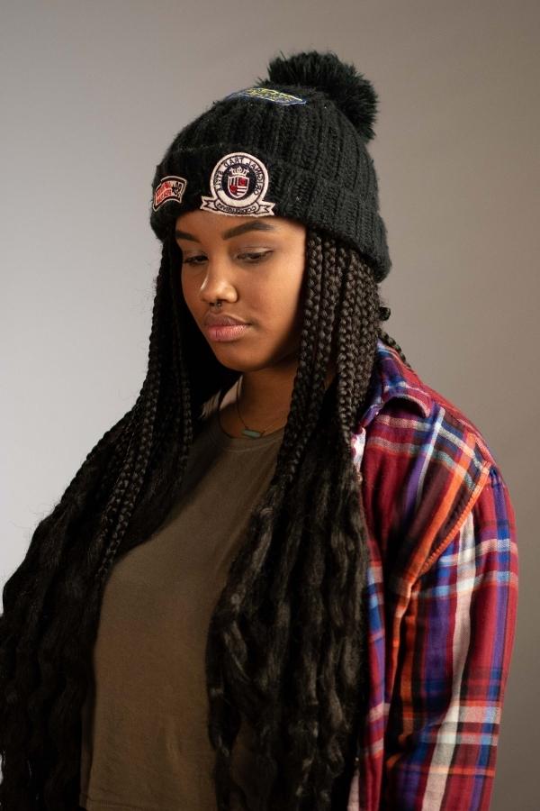 arafed woman with long hair wearing a black hat and plaid shirt