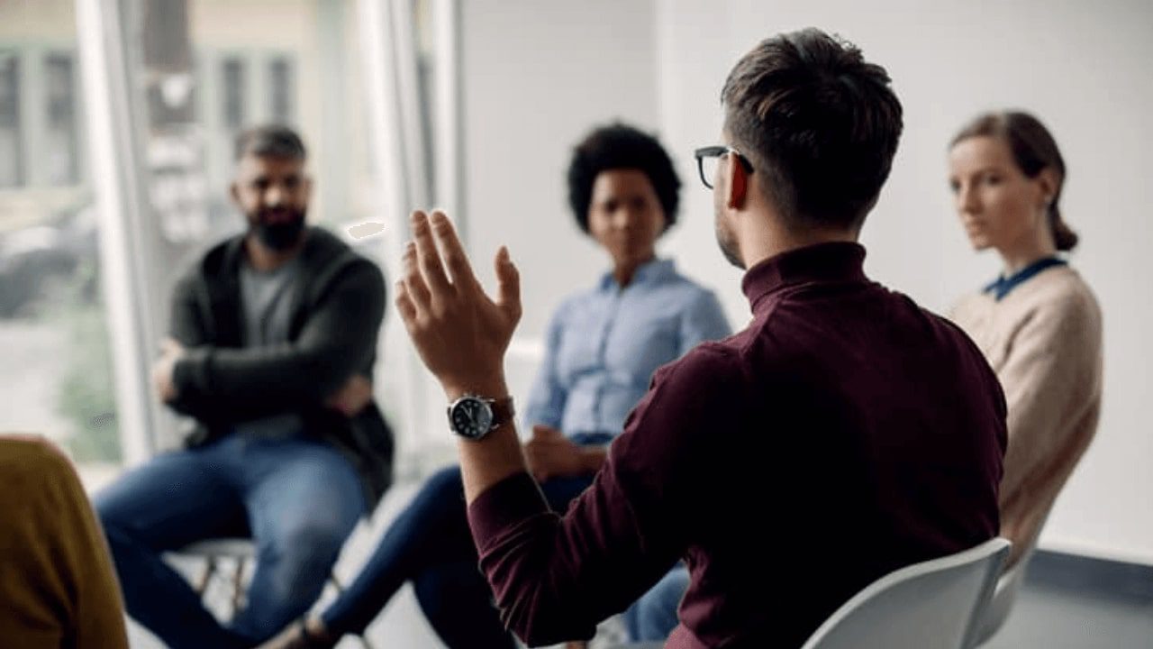 several people sitting in chairs in a room with one person raising his hand
