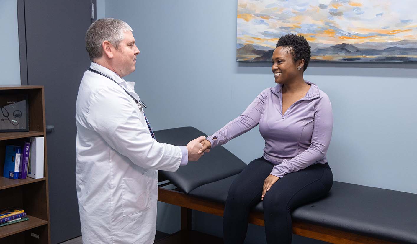 doctor shaking hands with a patient in a room with a painting