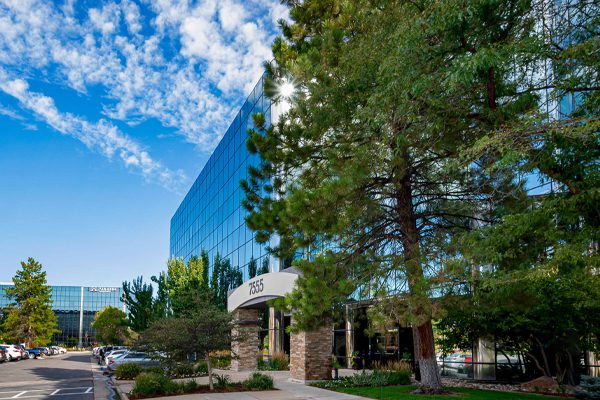 a view of a building with a parking lot and trees