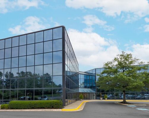 a large glass building with a parking lot in front of it