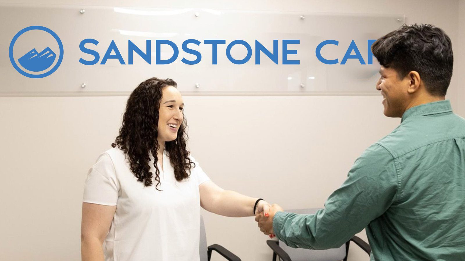 arafed woman shaking hands with a man in front of a sign