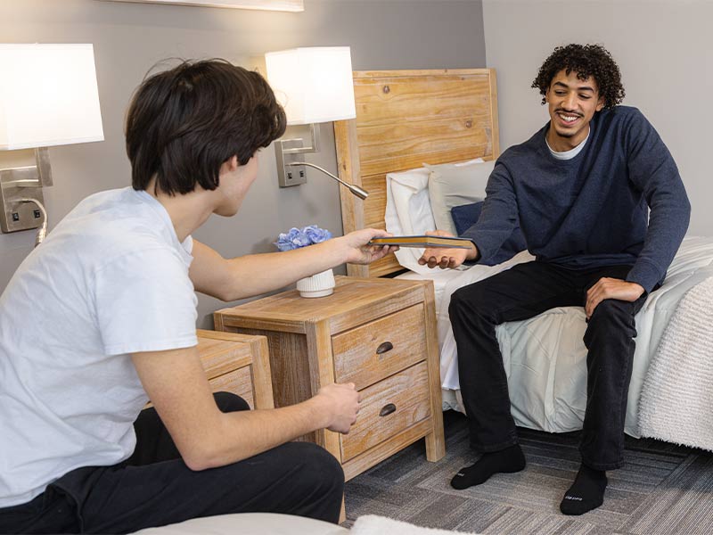 there is a man sitting on a bed with a woman sitting on the bed