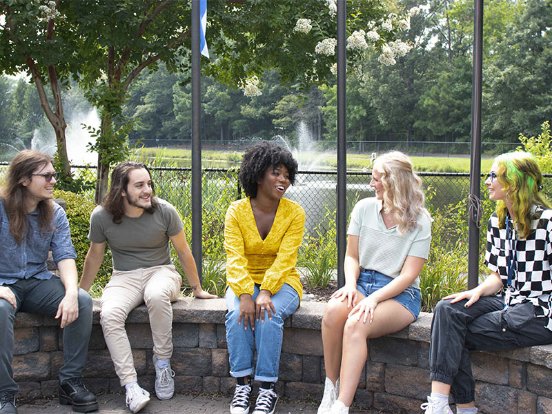 several women sitting on a stone wall talking to each other