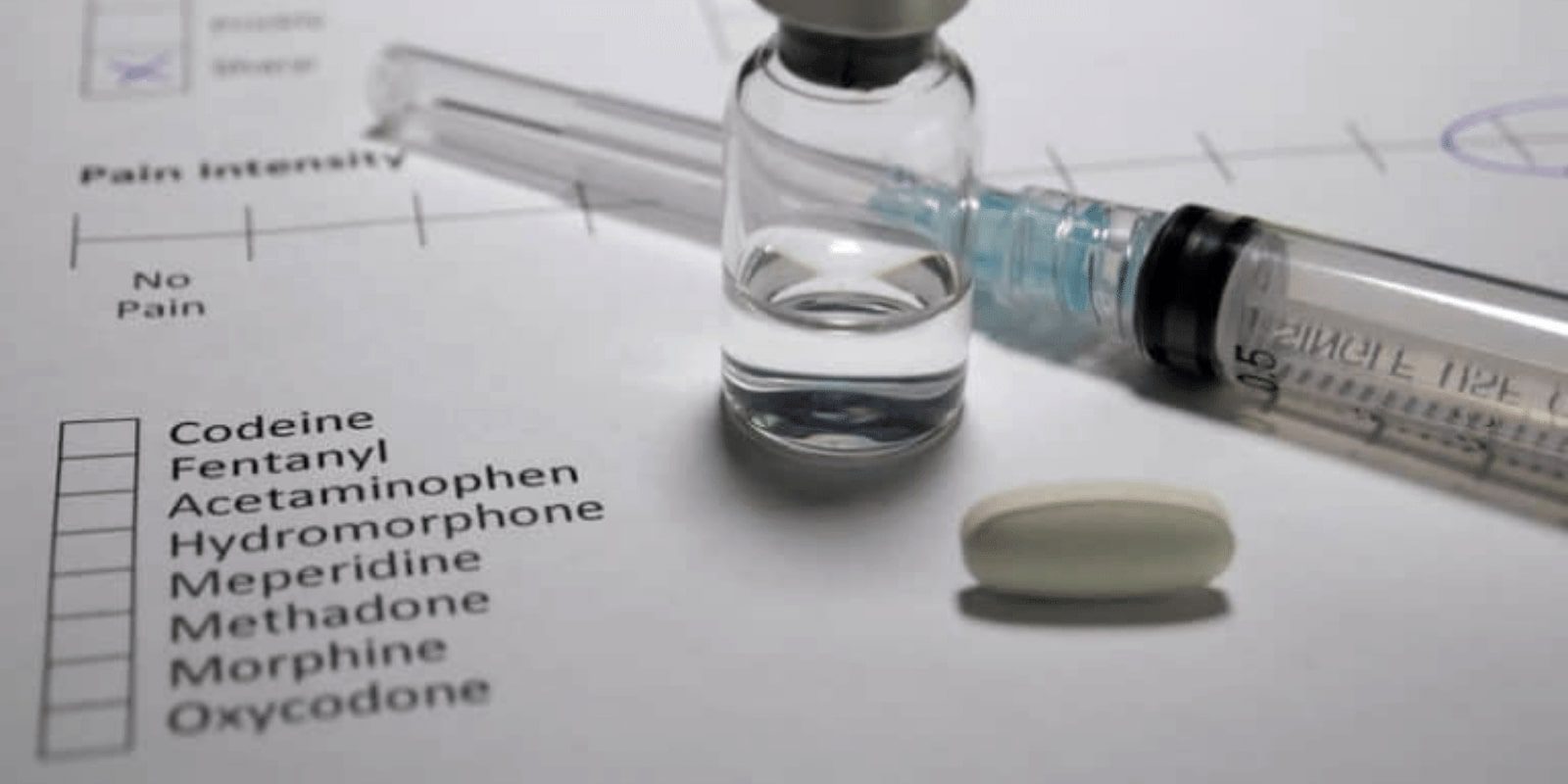 Bottle of substance and a needle on a paper