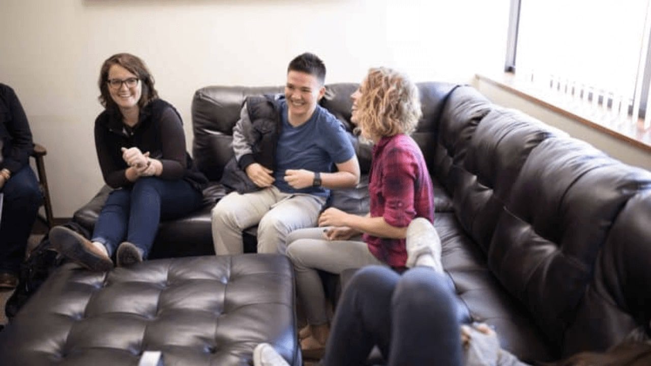 several people sitting on a couch in a room with a black leather couch