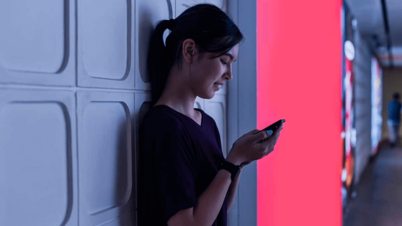 there is a woman standing against a wall looking at her cell phone