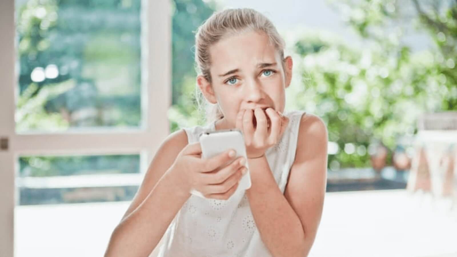 teen looking apprehensive with phone in hand